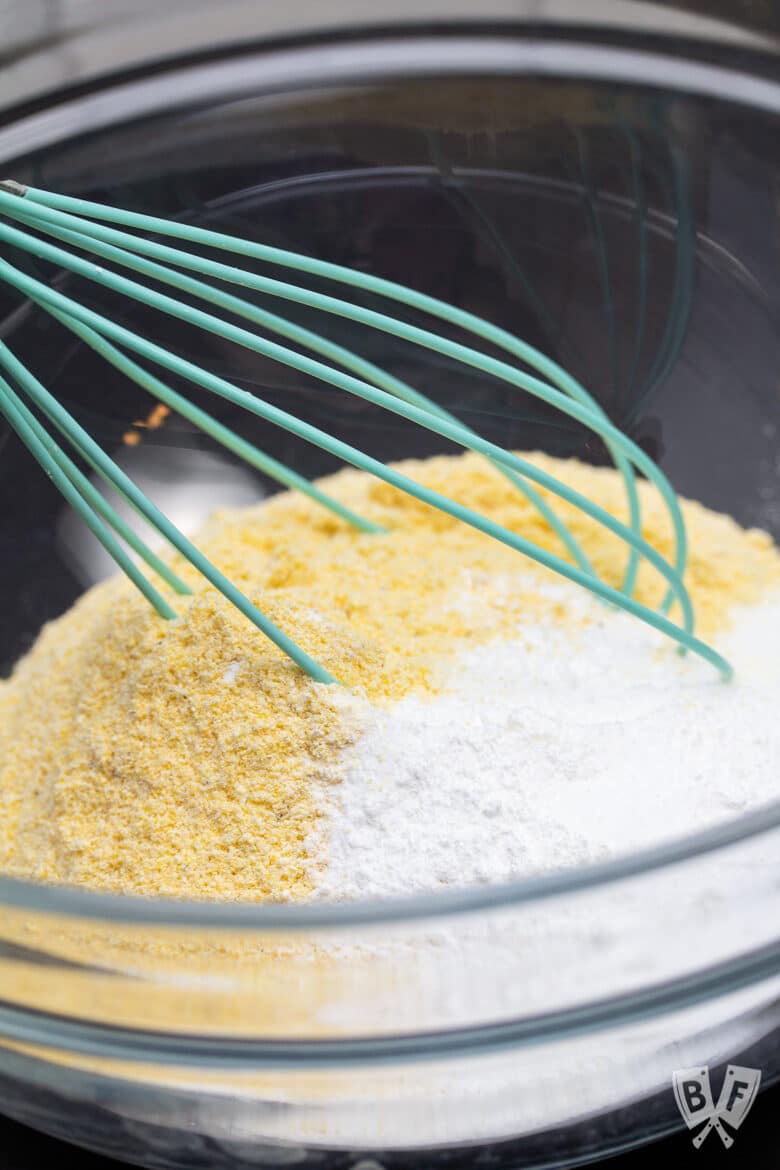 Whisking dry ingredients in a bowl for sweet corn muffin recipe.