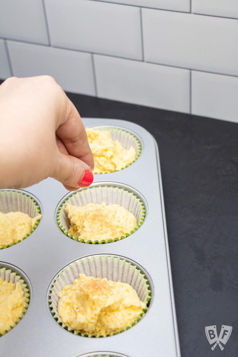 Sprinkling turbinado sugar on top of sweet corn muffins.