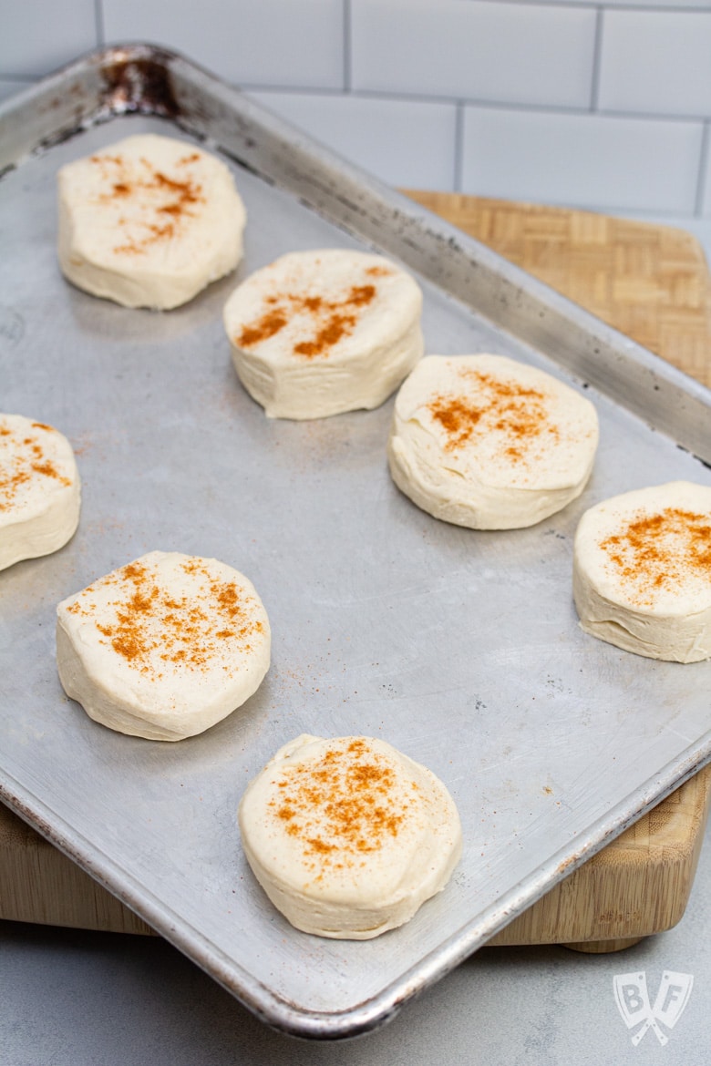 A sheet pan of canned biscuits sprinkled with cayenne pepper and sweet paprika.