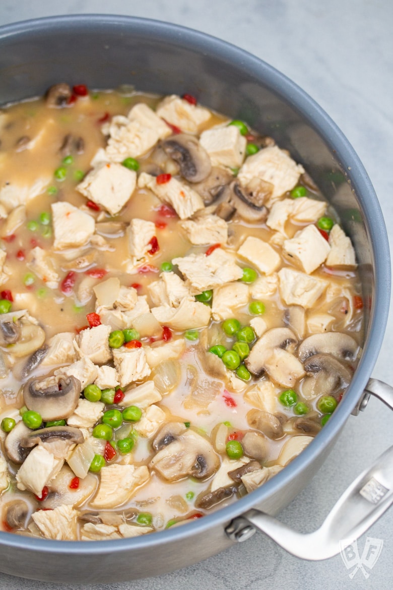 Chicken and veggies simmering in a saucepan.