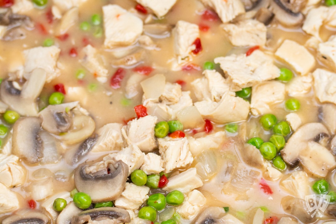 Chicken and veggies simmering in a saucepan.