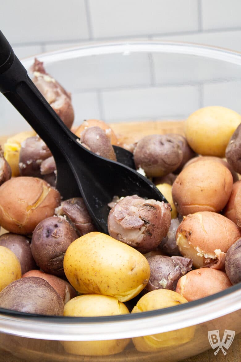 Mashing boiled baby potatoes in a bowl for potato salad.