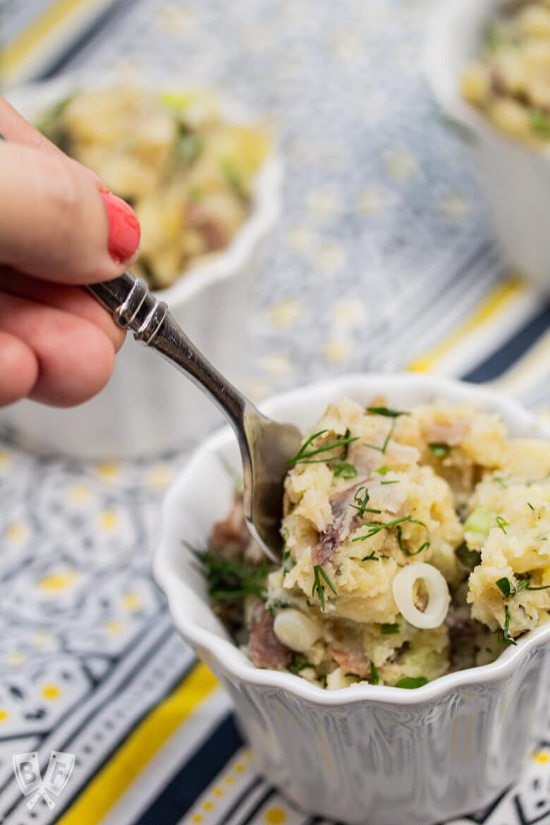 Fork going into a bowl of herbed potato salad.