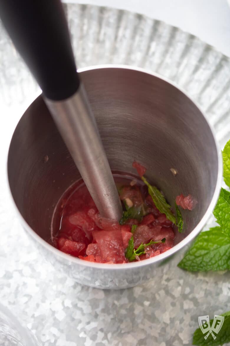 Muddled watermelon and mint in a cocktail shaker.