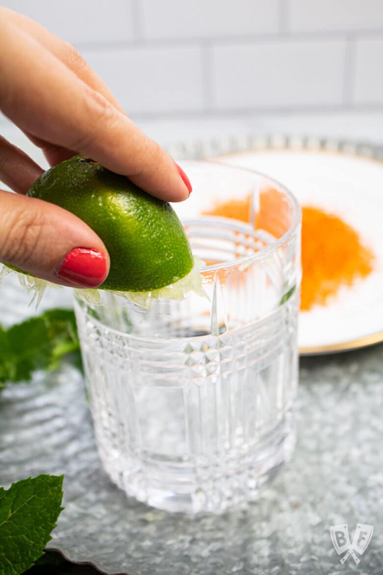 Rubbing a lime on the rim of a cocktail glass.