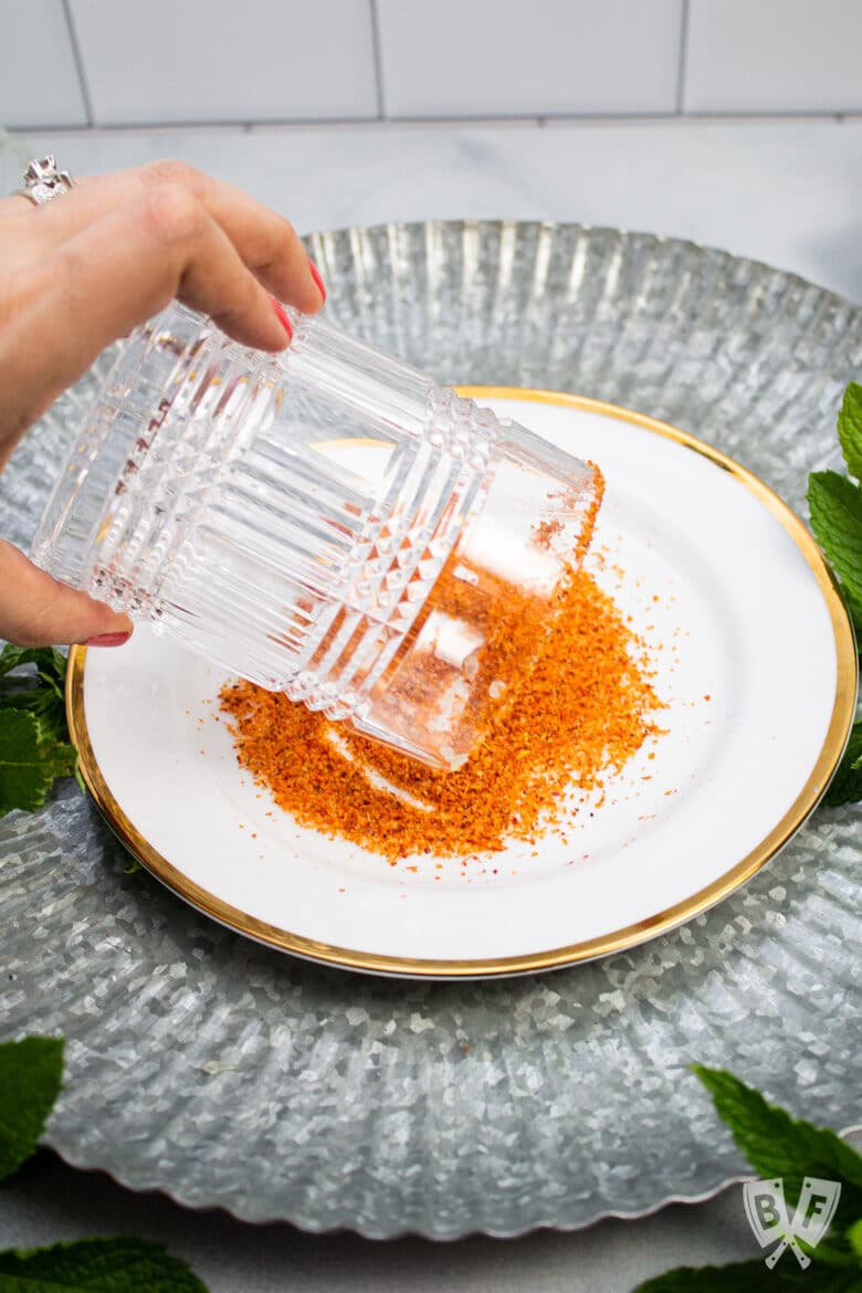 Rimming a cocktail glass with Tajín seasoning.