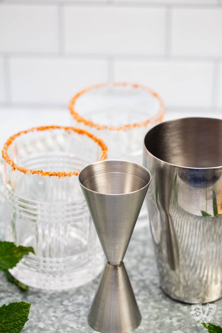 Tajín rimmed cocktail glasses with a jigger and cocktail shaker.