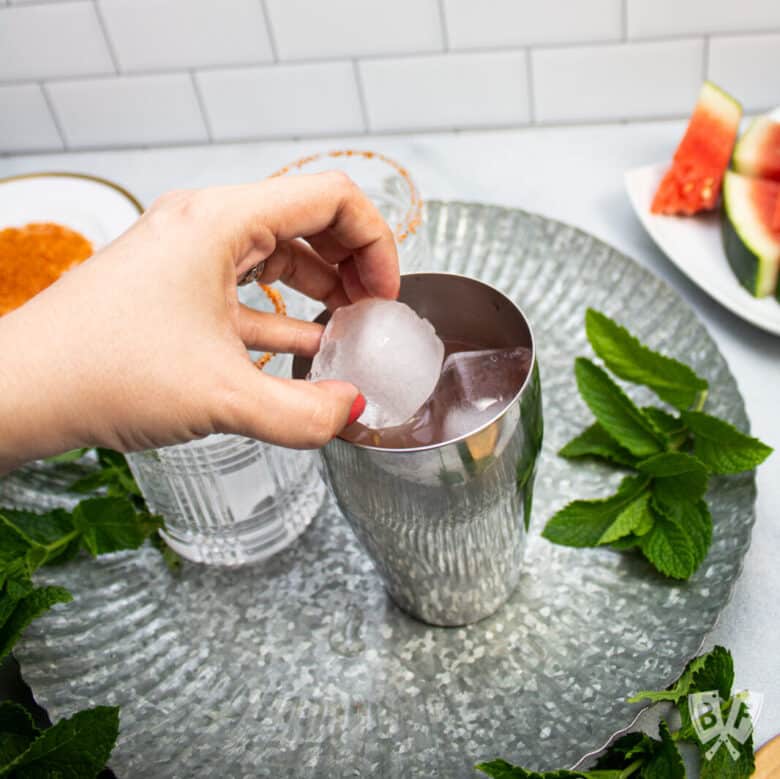 Placing ice cubes into a cocktail shaker.