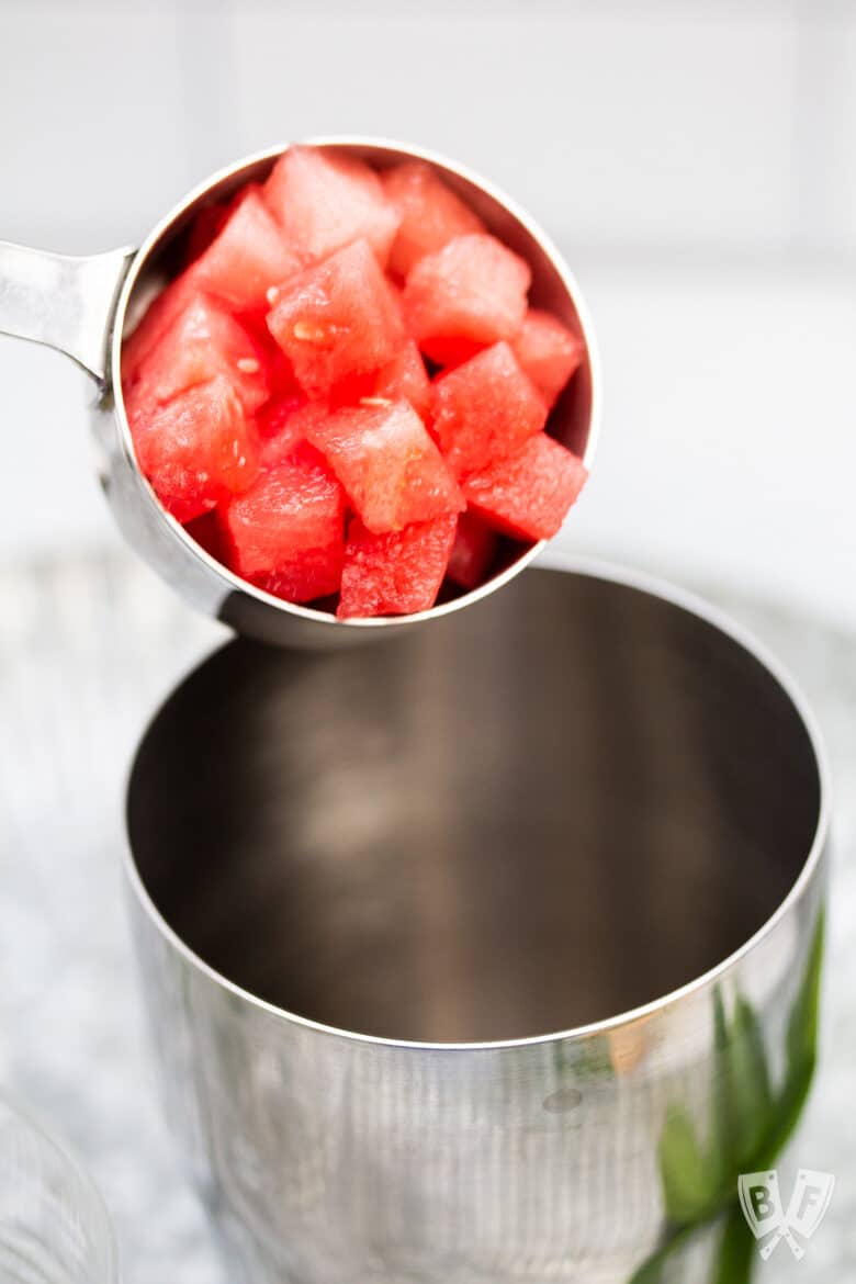 Pouring cubes of watermelon into a cocktail shaker.