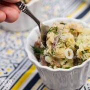 Fork going into a bowl of herbed potato salad.