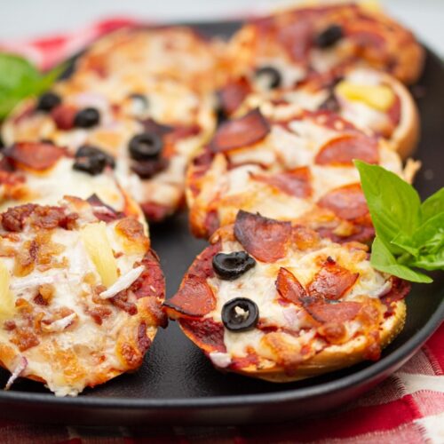 Close up of assorted mini pizza bagels on a platter.