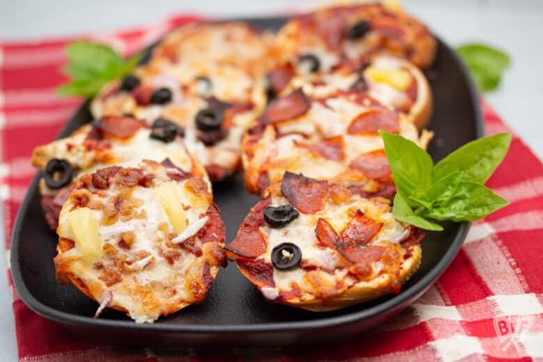 Close up of assorted mini pizza bagels on a platter.