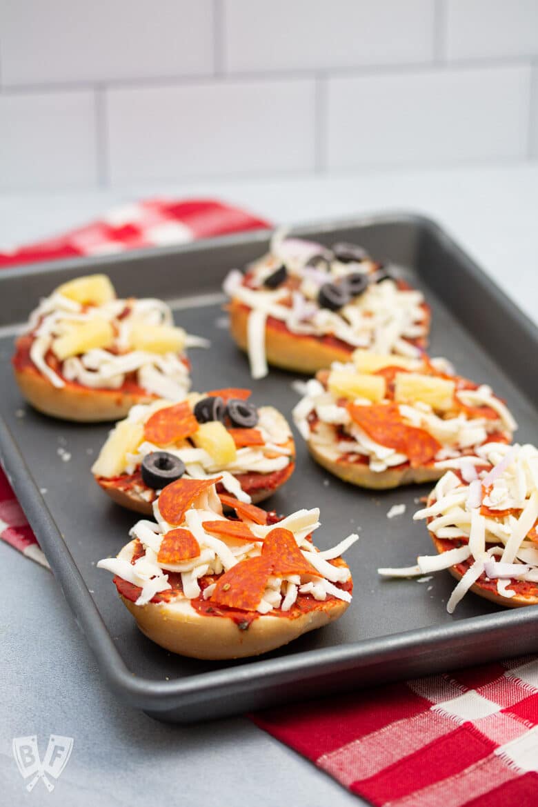 6 assorted mini pizza bagels on a sheet pan.