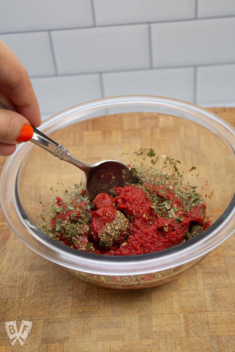 Mixing homemade pizza sauce ingredients in a bowl.