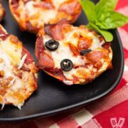 Close up of mini pizza bagels on a platter with fresh basil.