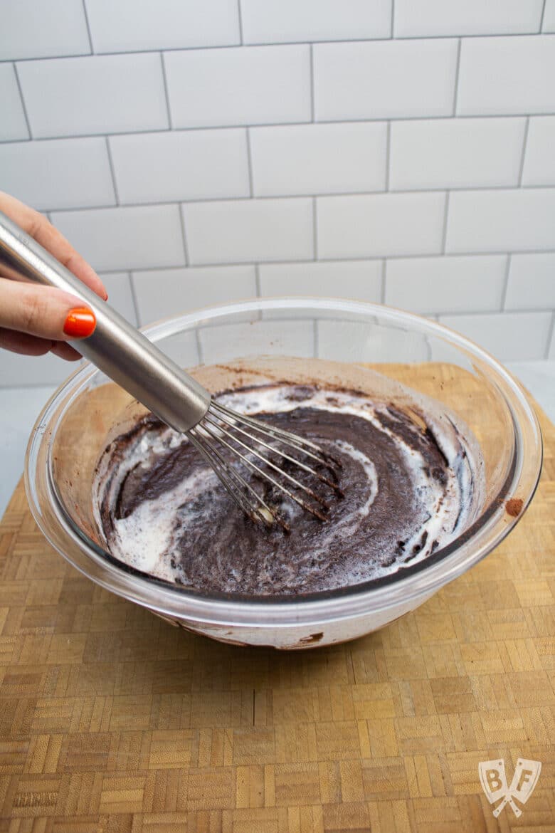 Whisking buttermilk into a glass bowl of chocolate.