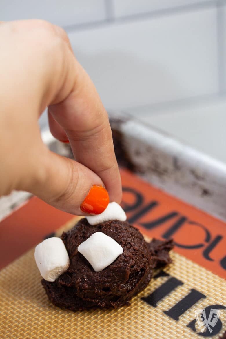 Pressing mini marshmallows into a ball of chocolate cookie dough.