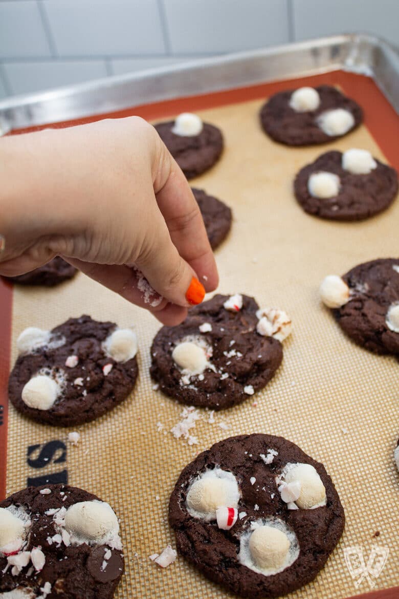 Sprinkling crushed peppermint candy on top of freshly baked cookies.