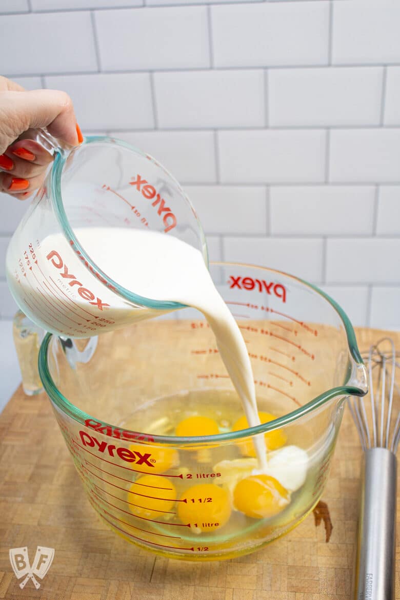 Pouring milk into a large measuring cup with eggs.