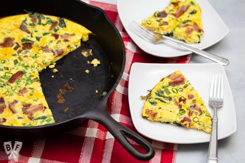 Frittata in a cast iron skillet with a few slices taken out on plates to the side.