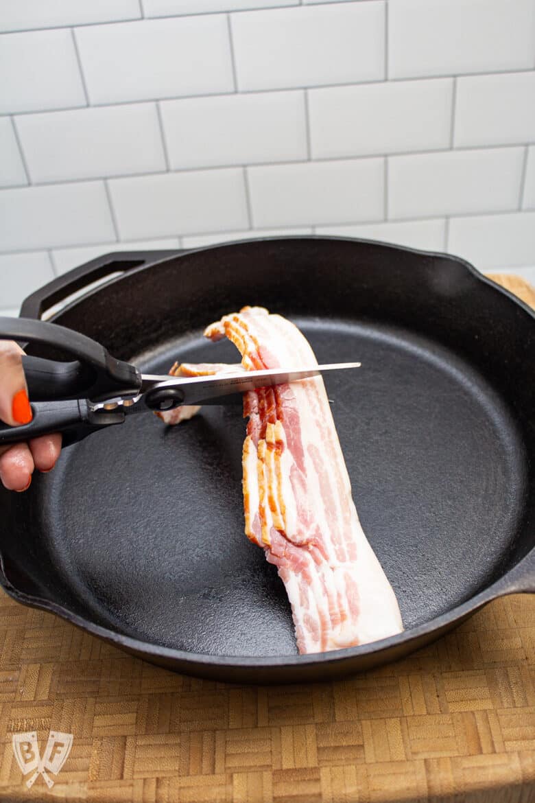 Cutting bacon over a cast iron skillet with kitchen scissors.