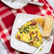 Two wedges of spinach, bacon, green onion, and cheddar frittata with toasted English muffin slices.