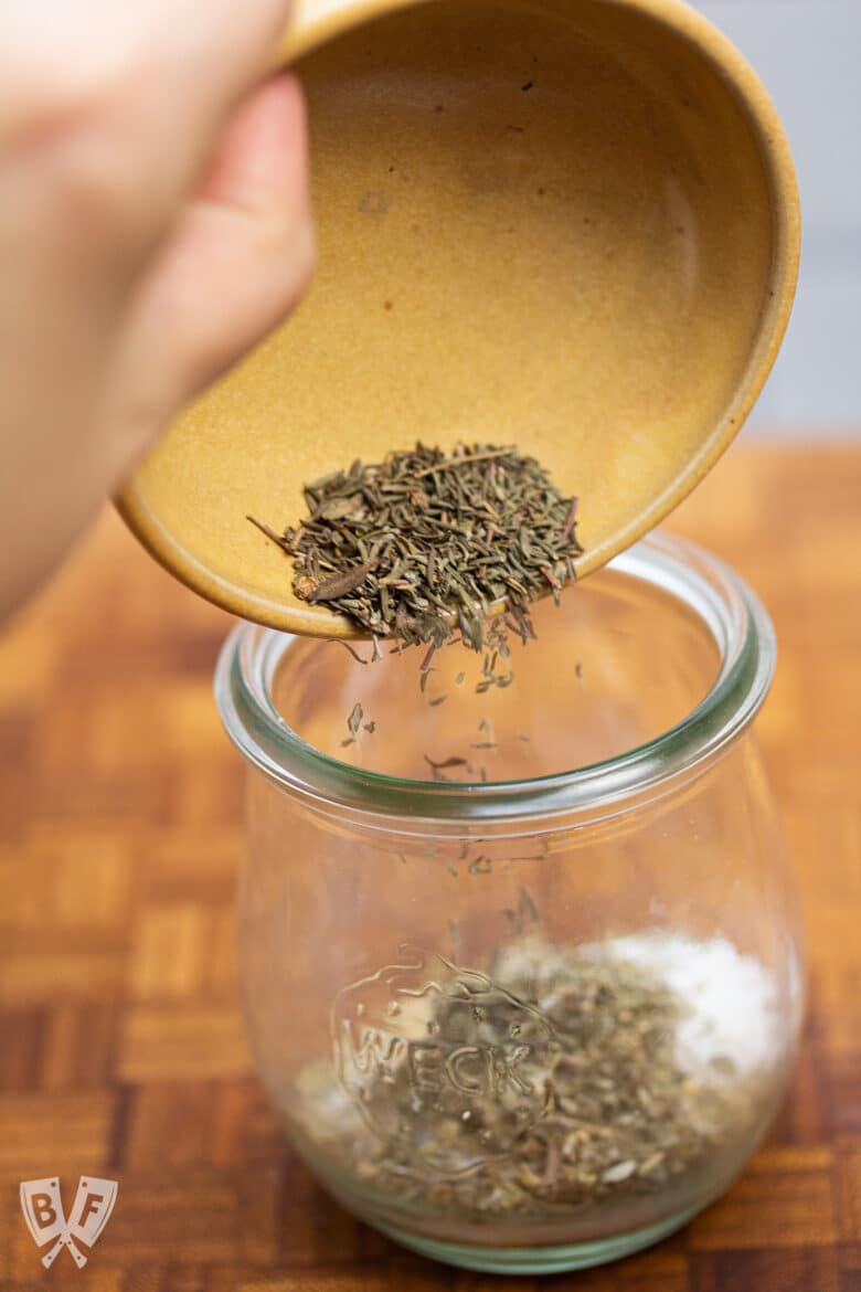 Pouring dried thyme into a jar.