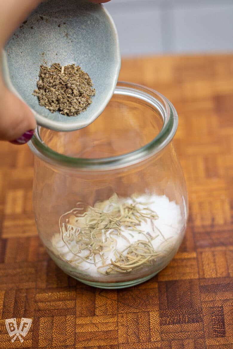 Pouring rubbed sage into a jar.