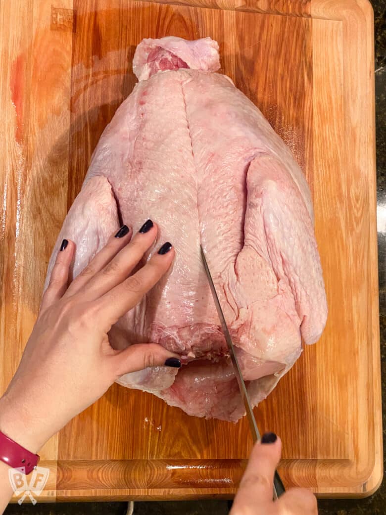 Scoring the skin on one side of the backbone of a turkey.