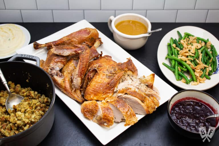 Sliced roast turkey on a platter surrounded by Thanksgiving side dishes.