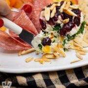 Cutting into a mini gorgonzola fruit torta on a cheese board.