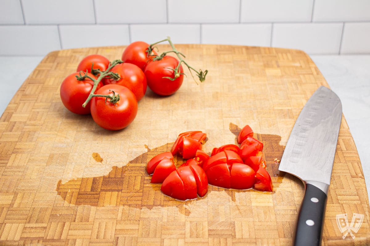 Chopping tomatoes on a cutting board.