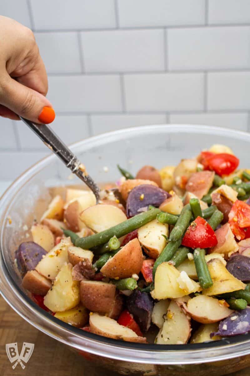 Stirring a bowl of Calabrese potato salad to combine.