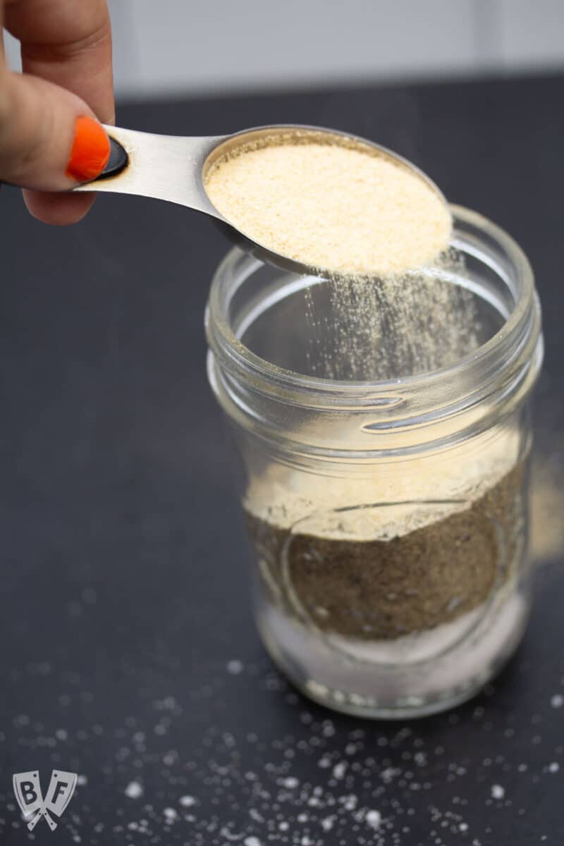 Pouring garlic powder into a glass jar.