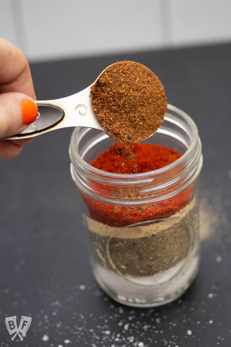 Pouring chili powder into a glass jar.