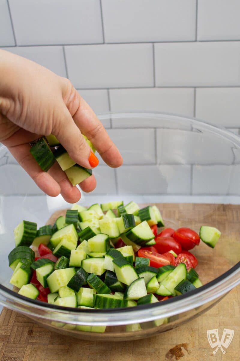 Adding cucumbers to a bowl of tomatoes.