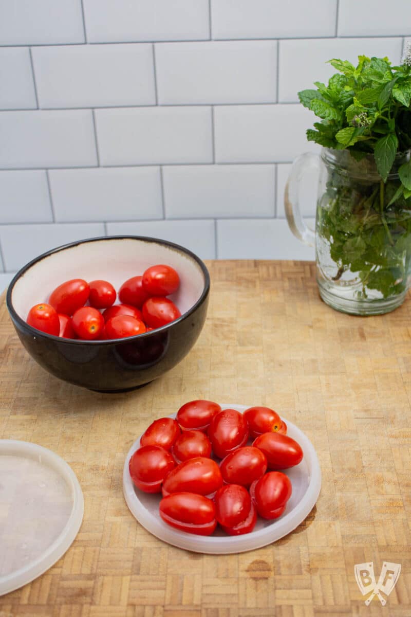 Sliced tomatoes and a glass of fresh herbs.