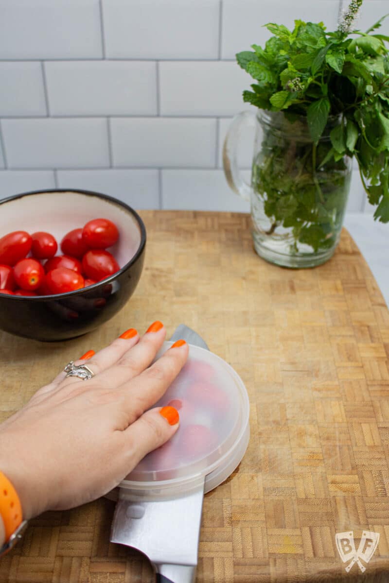 Slicing grape tomatoes in half with a knife.