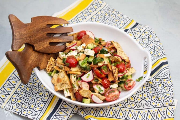 Bowl of fattoush salad with serving utensils.