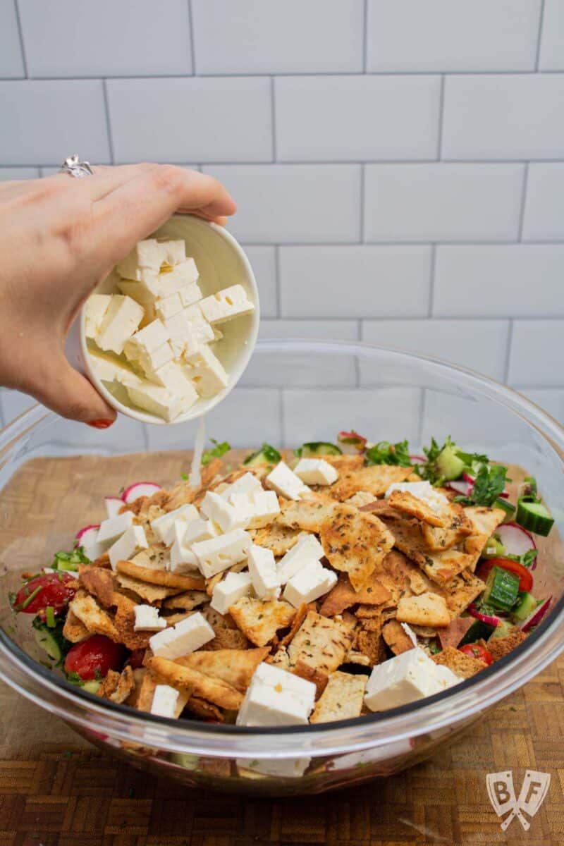 Adding feta cheese to a salad.