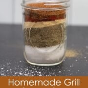 Layers of spices for homemade grill seasoning in a glass jar.