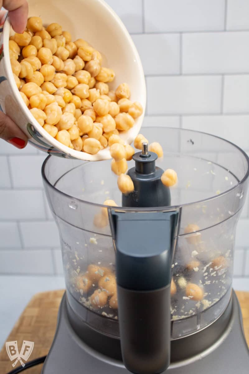 Adding chickpeas to a food processor.