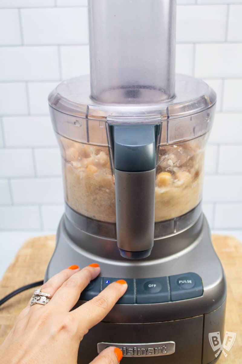 Combining ingredients for hummus in a food processor.