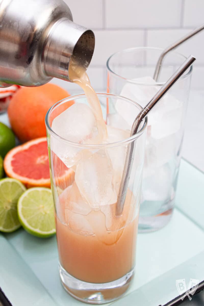 Pouring a guava cocktail into a glass of ice.