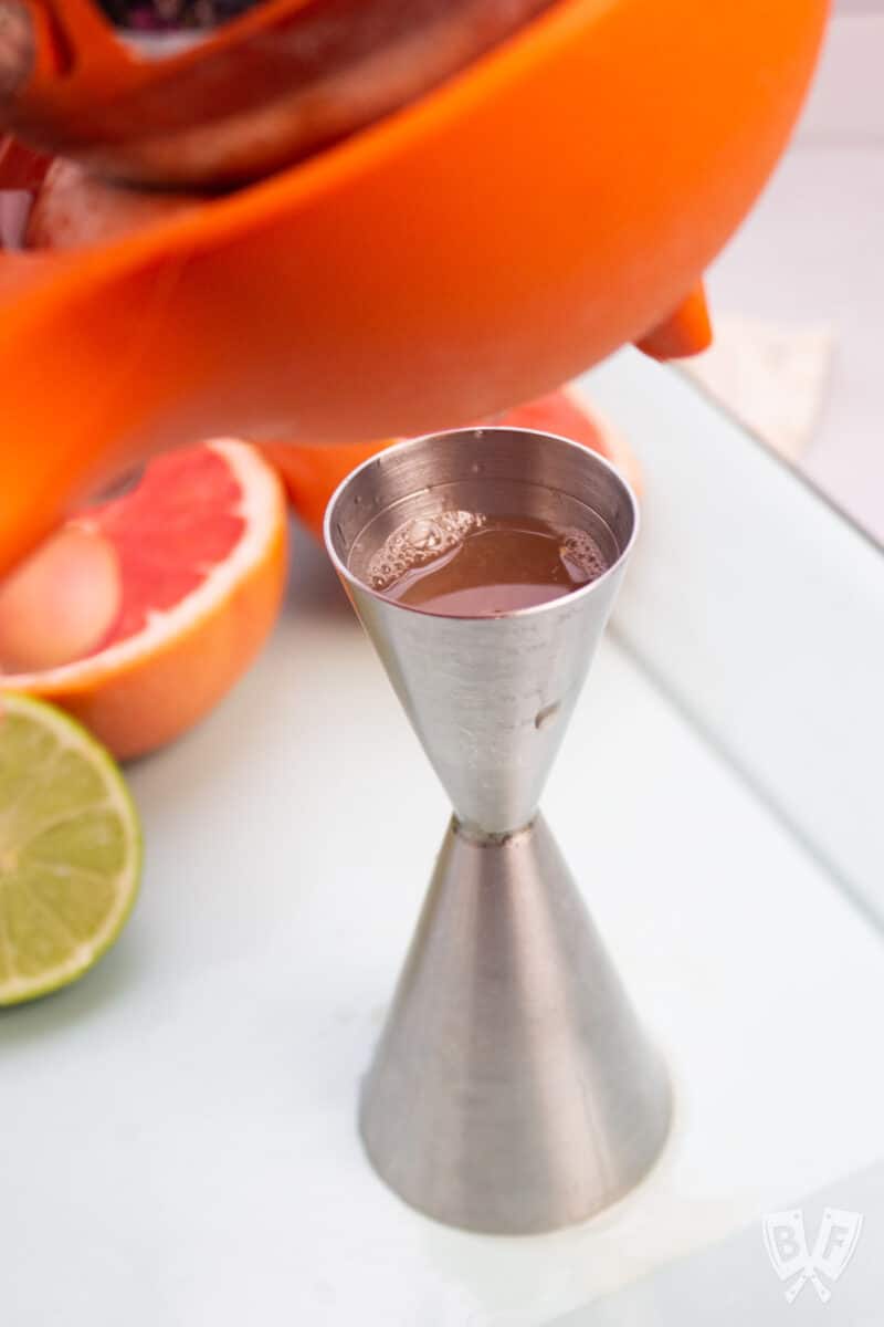 Squeezing grapefruit juice into a jigger.