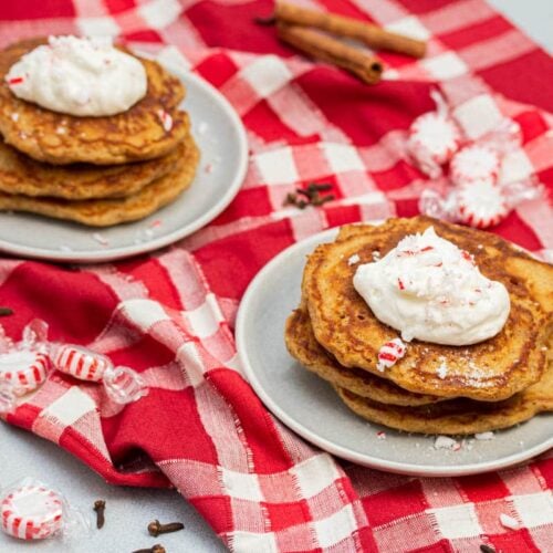2 plates of gingerbread pancakes topped with whipped cream & peppermint.