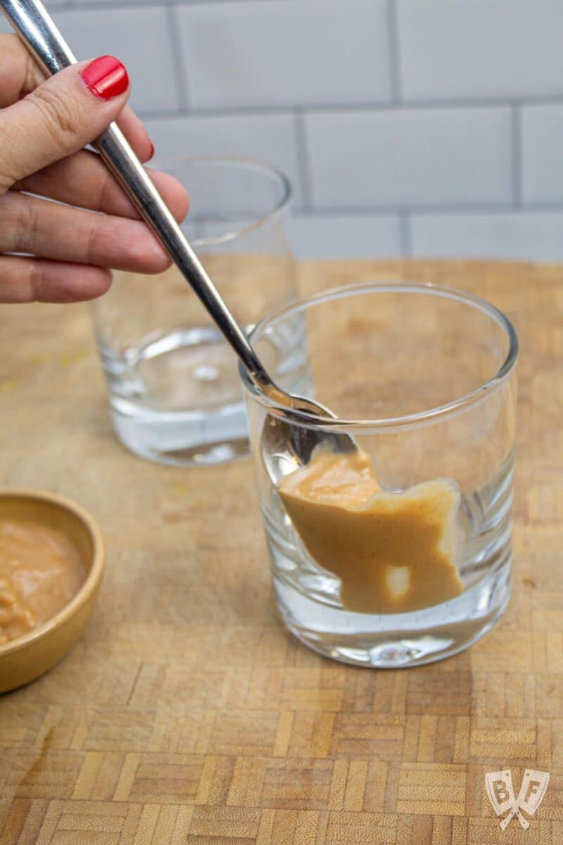 Placing peanut butter around the inside of a glass.