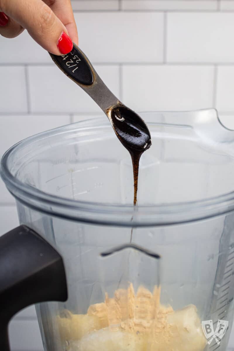 Adding vanilla bean paste into a blender with frozen bananas.