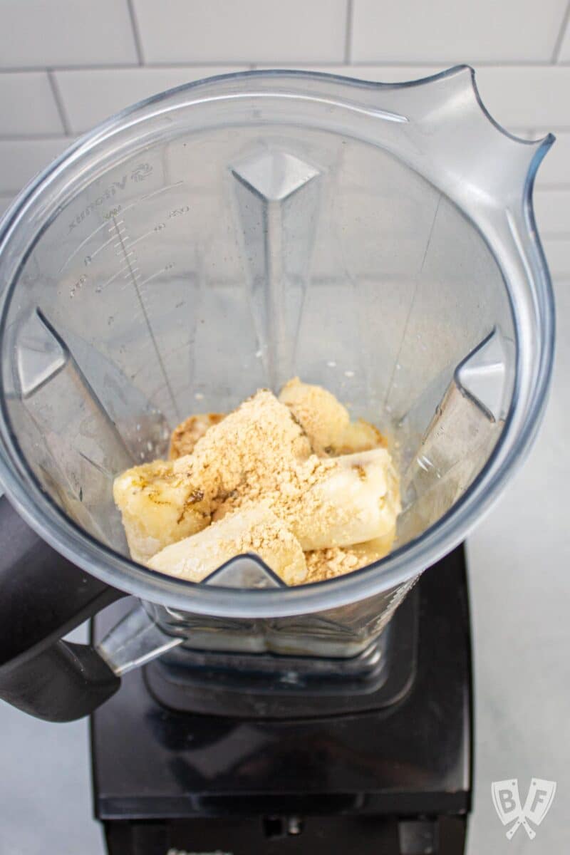 Overhead view of a blender with peanut butter banana milkshake ingredients inside.