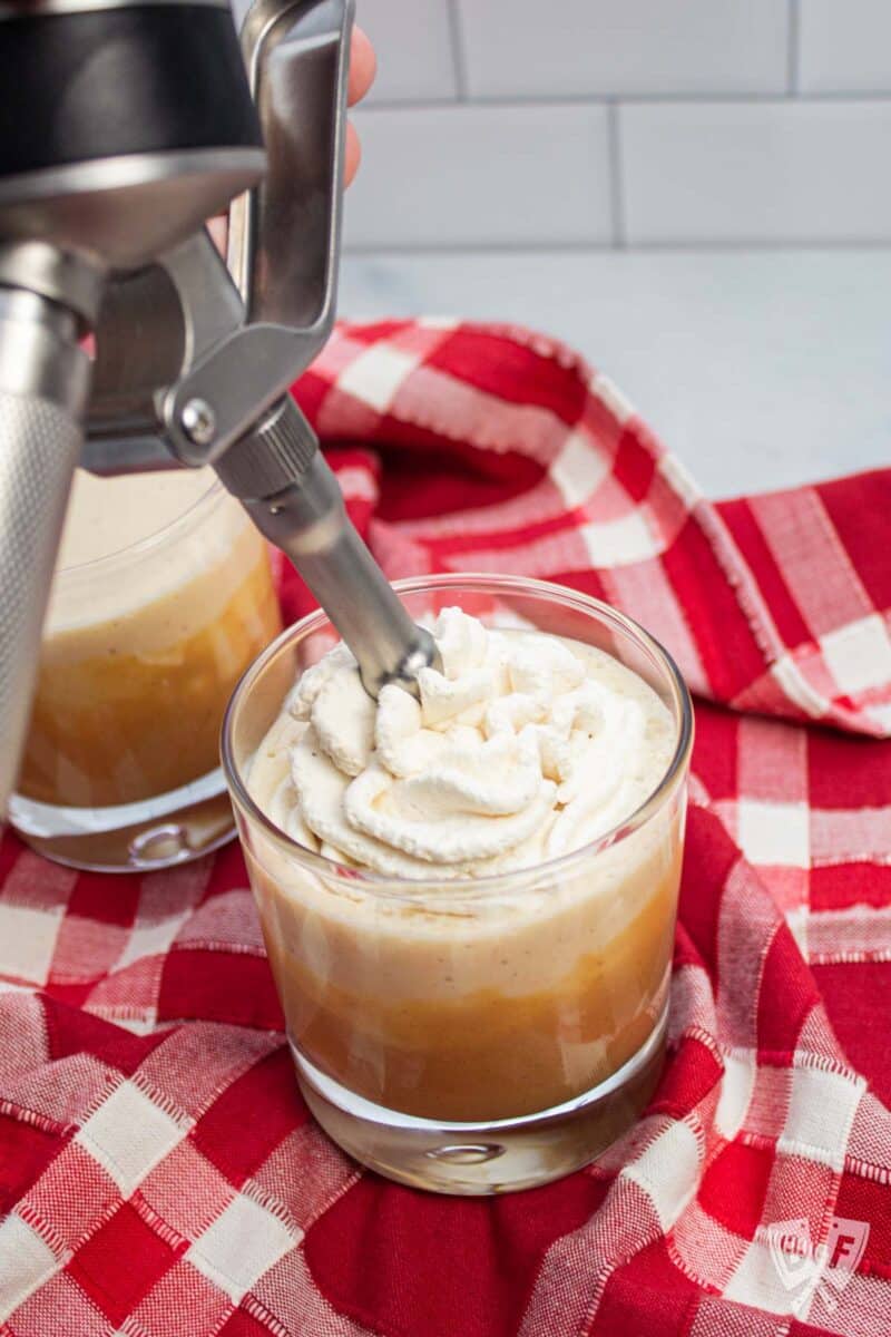 Topping a peanut butter banana milkshake with whipped cream.